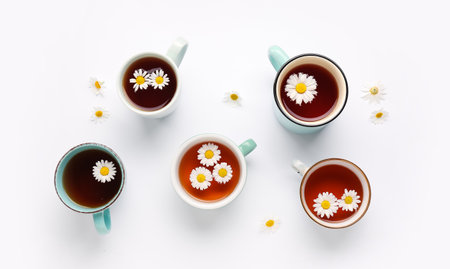 Cups of natural chamomile tea and flowers on white backgroundの写真素材
