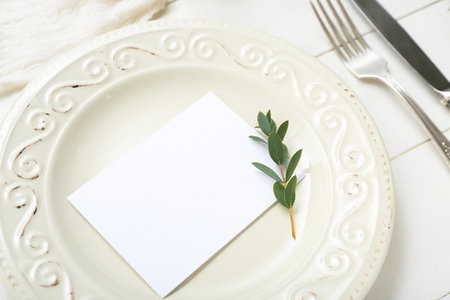 Plate with cutlery, blank card and plant branches on white wooden backgroundの写真素材