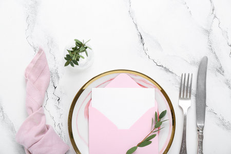 Stylish table setting, envelope with blank card and vase of plant branch on grunge white backgroundの写真素材