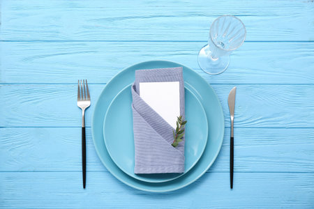 Stylish table setting with blank card and glass on blue wooden backgroundの写真素材