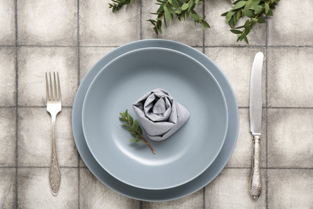 Beautiful table setting with plant branches on gray tile background
