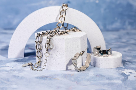 Decorative podiums with beautiful jewelry on blue background