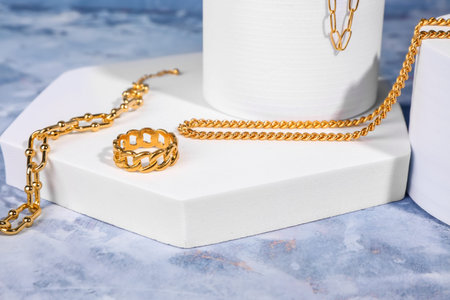 Decorative podiums with beautiful jewelry on blue background