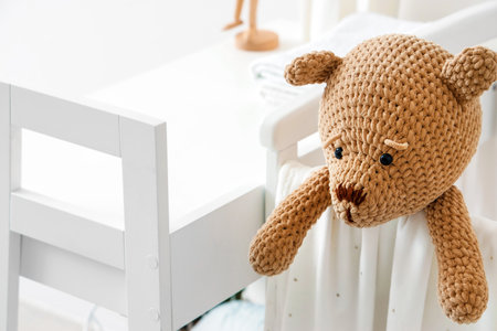 Baby crib with toy bear in light bedroom, closeupの写真素材