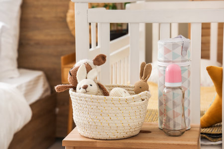 Baby bottle with toys on stool in bedroom, closeupの写真素材