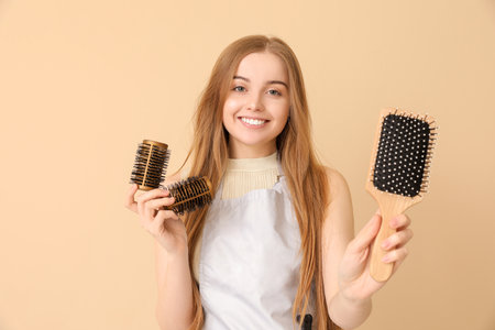 Female hairdresser with curlers and brush on beige backgroundの写真素材