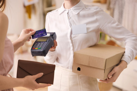 Female customer paying for her purchase with credit card in boutique, closeup