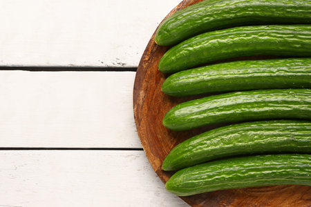 Plate with fresh cucumbers on light wooden background, closeupの写真素材