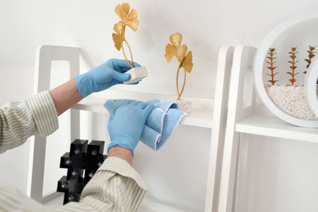 Male janitor cleaning shelf in living room, closeup
