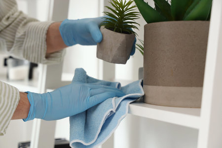 Male janitor cleaning shelf in living room, closeup