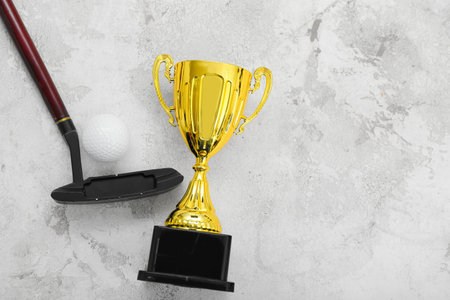 Gold cup with golf club and ball on grunge background