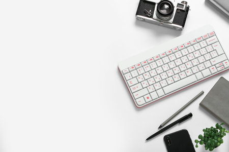 Composition with keyboard, photo camera, mobile phone and pens on white background