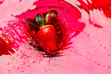 Falling of ripe strawberry into red juiceの写真素材