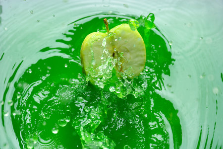 Falling of ripe apple into green juiceの写真素材