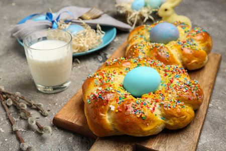 Wooden board with tasty Italian Easter bread, eggs and glass of milk on grunge background, closeupの写真素材
