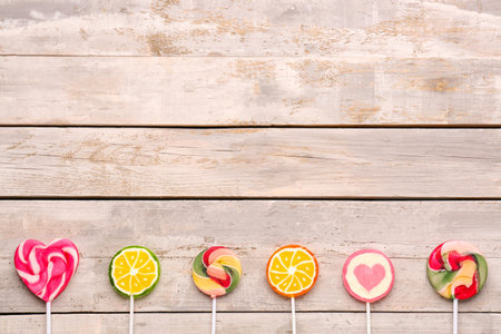 Different sweet lollipops on weathered wooden tableの写真素材