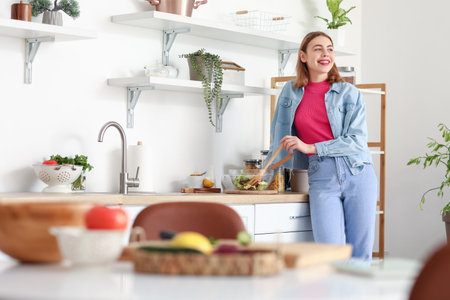 Young woman making vegetable salad in the kitchenの写真素材