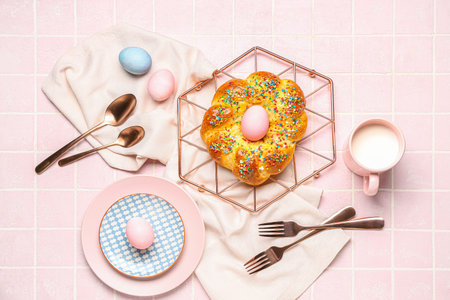Table setting with tasty Italian Easter bread and eggs on pink tile background