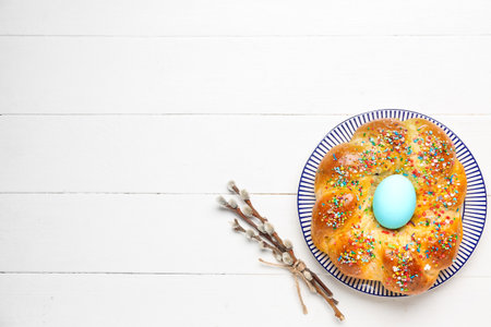 Plate with tasty Italian Easter bread and willow branches on white wooden backgroundの写真素材