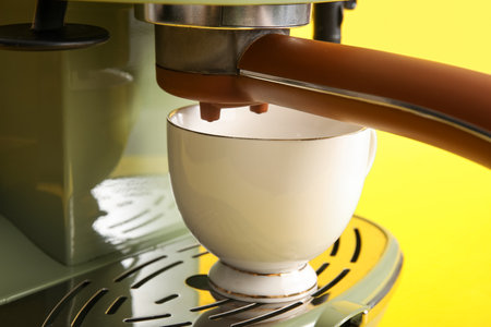 Modern coffee machine with cup on yellow background, closeupの写真素材