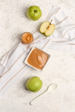 Composition with bowl of healthy baby puree and fresh apples on light backgroundの写真素材