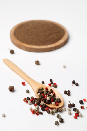 Wooden spoon with aromatic peppercorns on light backgroundの写真素材