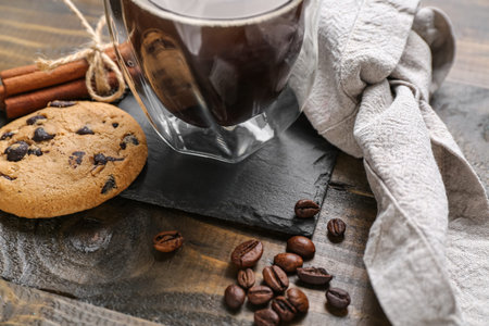 Drink coaster with cup of coffee, cookies and beans on wooden tableの写真素材