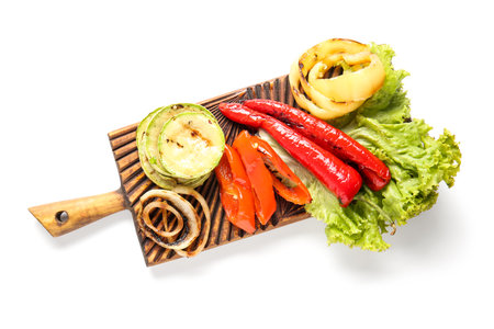 Wooden board with different tasty grilled vegetables on white backgroundの写真素材