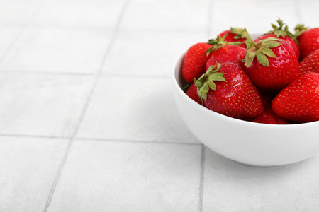 Bowl with fresh strawberries on white tile backgroundの写真素材