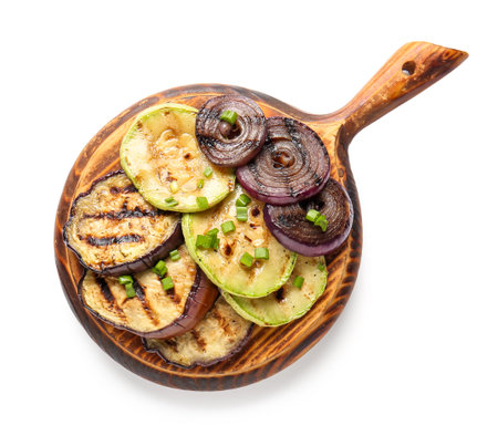 Wooden board with different tasty grilled vegetables on white backgroundの写真素材