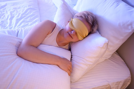 Young woman with mask sleeping in bed at nightの写真素材
