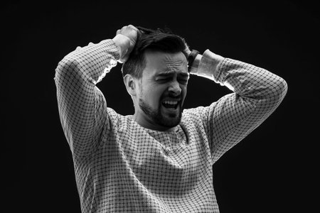 Young man having panic attack on black backgroundの写真素材
