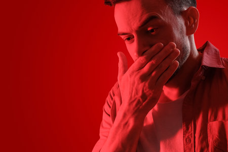 Young man having panic attack on red background, closeupの写真素材
