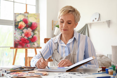 Mature female artist drawing sketch in workshopの写真素材