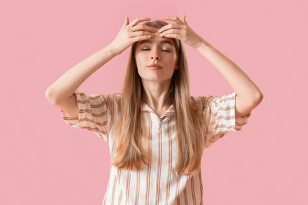 Young woman doing face building exercise on pink backgroundの写真素材