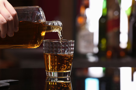 Woman pouring tasty rum from bottle into glass at table in barの写真素材