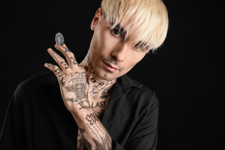 Tattooed young man with poker chip on black background, closeupの写真素材