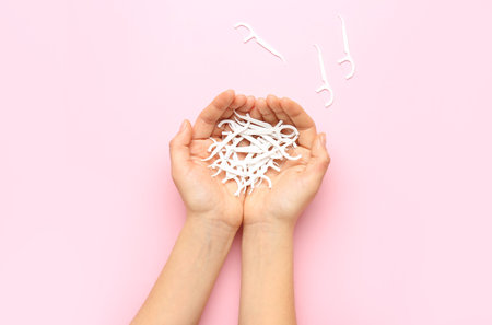Woman holding many floss toothpicks on pink backgroundの写真素材