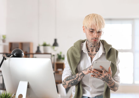 Young tattooed man working with tablet computer in officeの写真素材