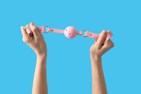 Woman with pink mouth gag from sex shop on blue backgroundの写真素材