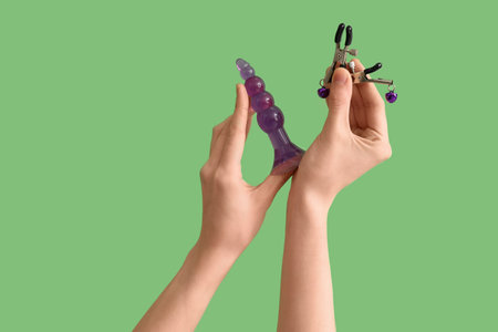 Woman with anal plug and nipple clamps from sex shop on green backgroundの写真素材