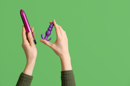 Woman with vibrator and anal plug from sex shop on green backgroundの写真素材