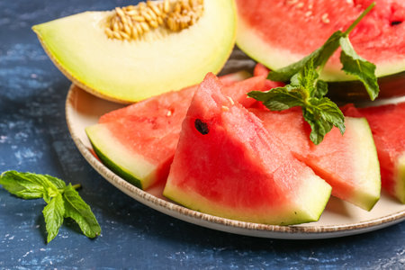 Plate with pieces of fresh watermelon and melon on blue backgroundの写真素材