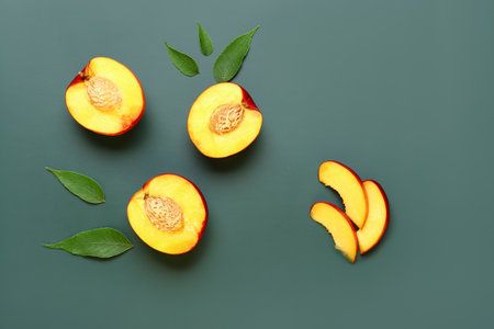 Halves of sweet peaches and leaves on green backgroundの写真素材