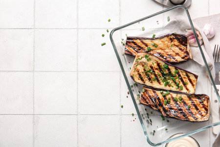 Glass casserole with delicious grilled eggplants on light backgroundの写真素材