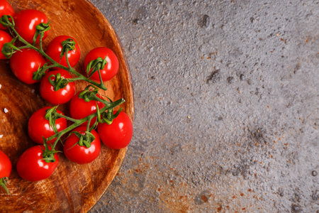 Wooden plate with fresh cherry tomatoes on dark backgroundの写真素材