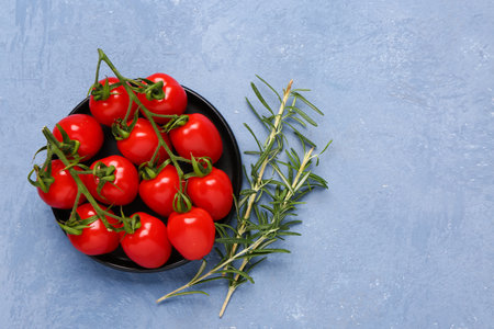 Tray with fresh cherry tomatoes and rosemary on blue backgroundの写真素材