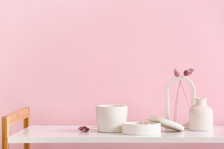 Holders with candles and decor on table near pink wall in roomの写真素材