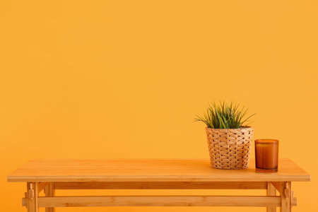 Wooden table with houseplant and candle near orange wallの写真素材