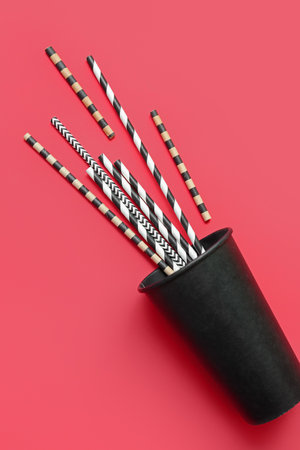 Black paper cup with different drinking straws on red backgroundの写真素材